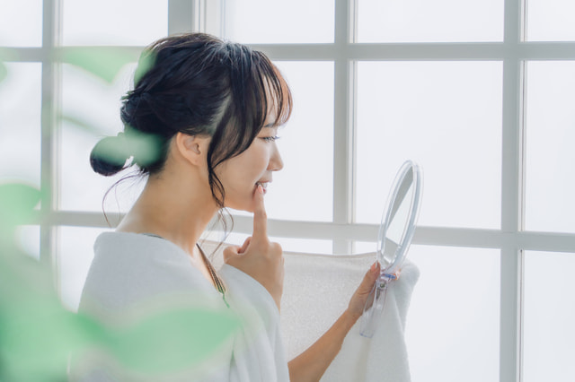 鏡で口元を確認する女性